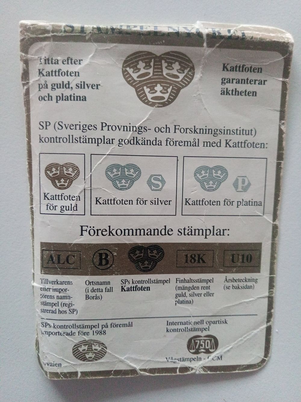 Stämpelnyckel från SP med kattfoten för guld, silver och platina samt exempel på stämplarna ALC, B, kattfoten, 18K och U10
